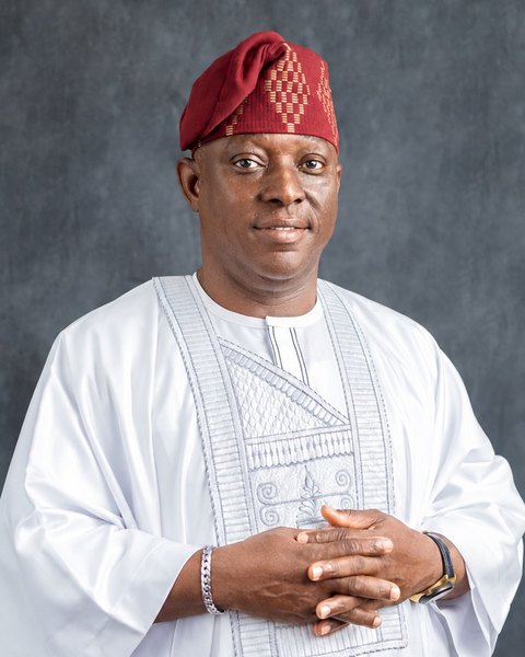 Kunle Olatunji, láti orí dé èjìká, pẹ̀lú fìlà pupa àti agbádá funfun